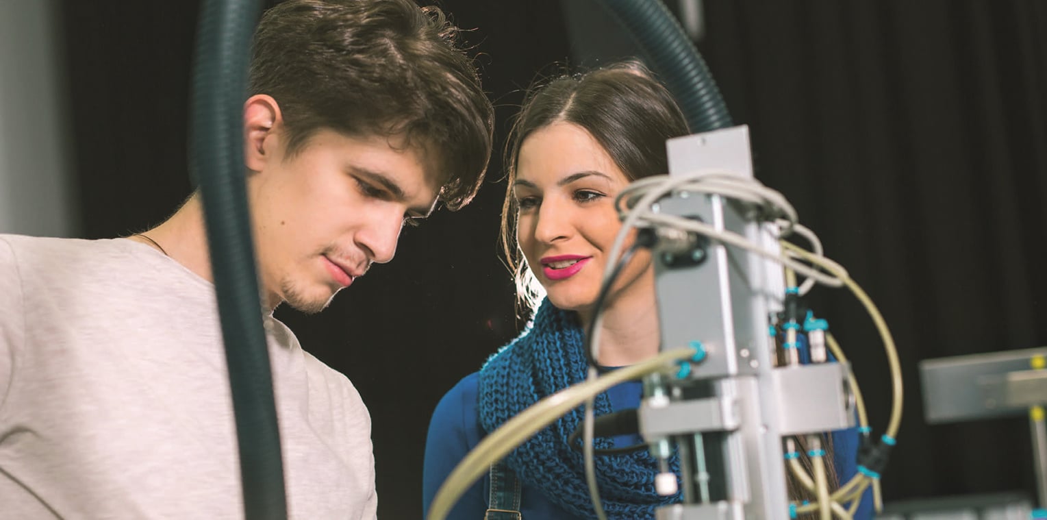 Un étudiant et une étudiante devant une machine